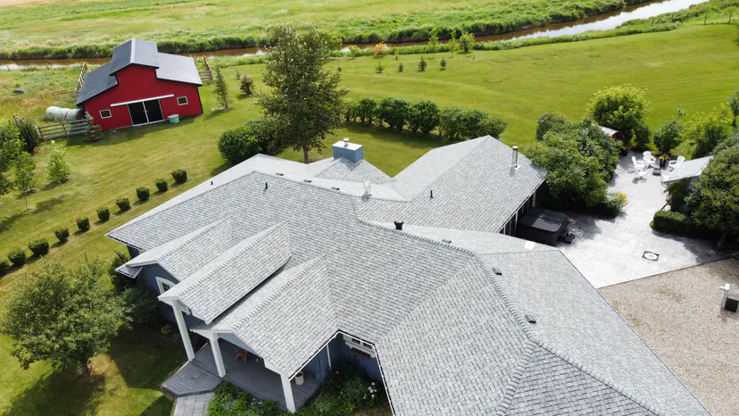 Close aerial view over the roof of the house, with the red barn, the creek and the back patio