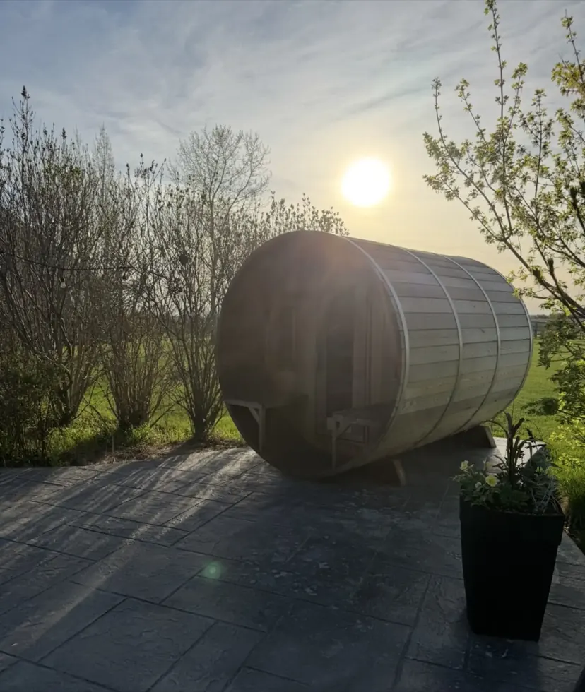 The cedar barrel sauna backlit by a low prairie sun.
