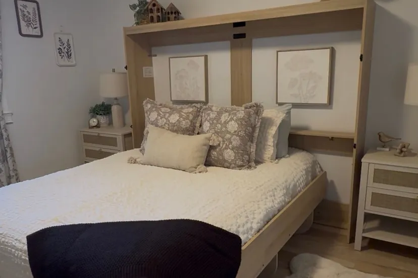 The upgraded Willow Room: a queen bed in a light wood fold-down surround, white textured bedding, floral pillows and pale bedside tables.